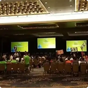 Conference room with multiple projection screens and seated audience during a presentation